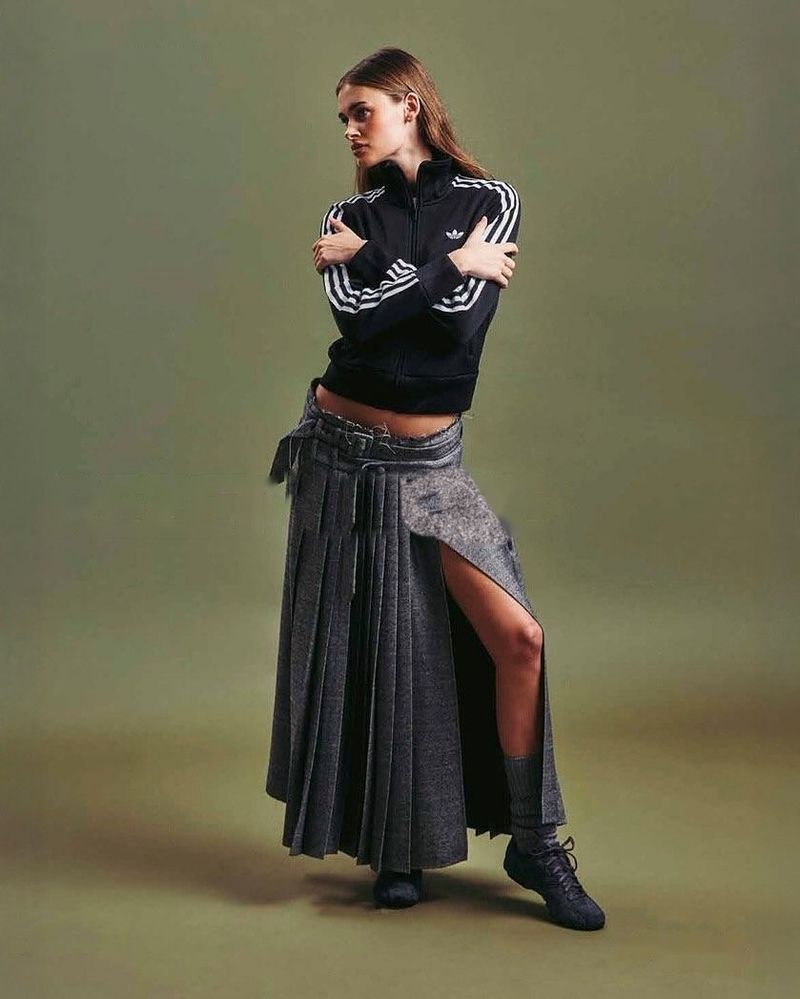 A model from the Rezet Store Lookbook Autumn Winter 2025 in a black track jacket and a long grey pleated skirt.