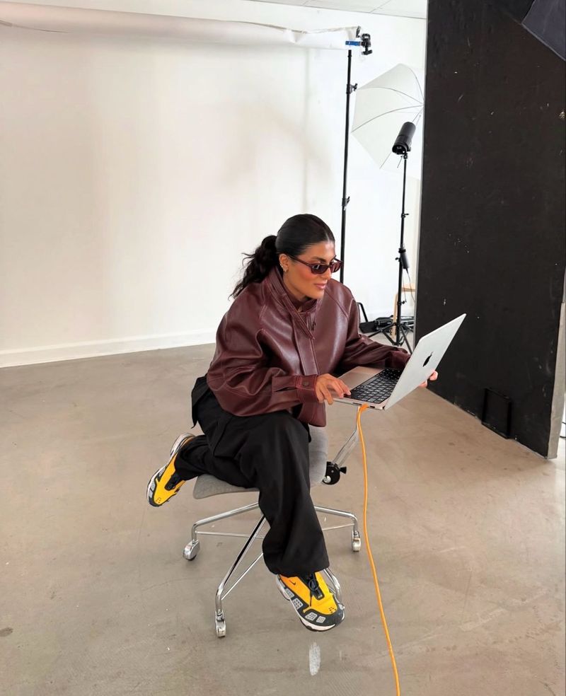 Sarah Al-farhan on set in a photo studio, working on a laptop.